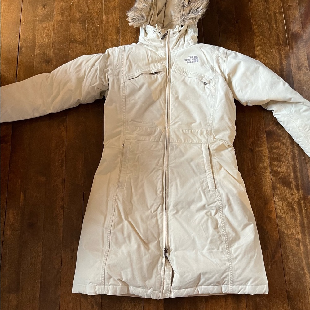 Cream-coloured long North Face winter jacket.